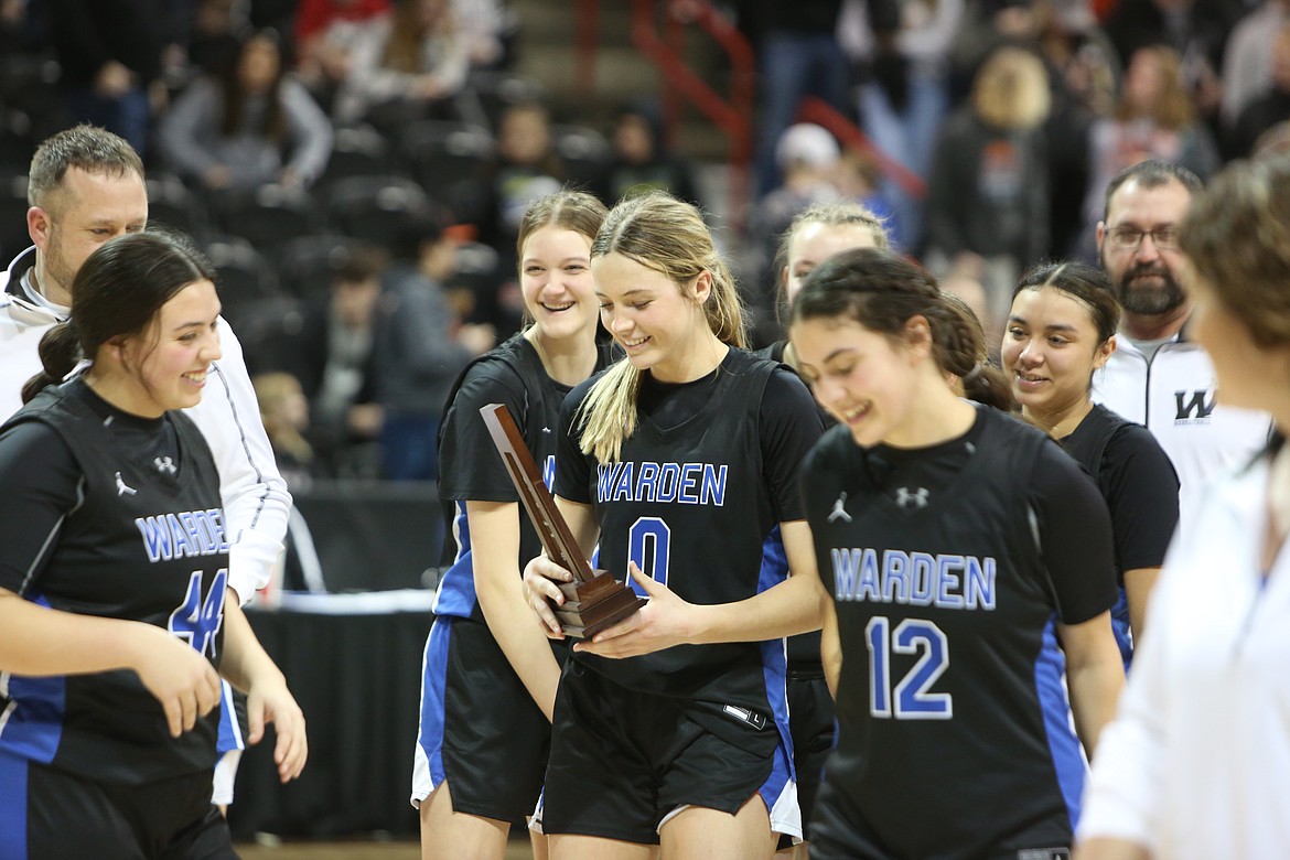 Warden junior Lauryn Madsen (0) smiles while holding the 2B girls state tournament’s third-place trophy after the Cougars defeated Napavine 54-47 on Saturday.