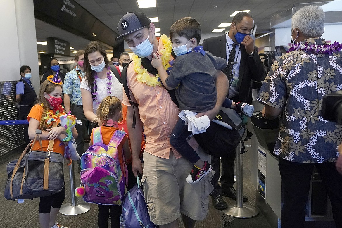 In this Oct. 15, 2020 file photo, Hawaii resident Ryan Sidlow carries his son Maxwell as their family boards a United Airlines flight to Hawaii at San Francisco International Airport in San Francisco. The Transportation Department is rolling out a “dashboard” to let travelers see at a glance which airlines help families with young children sit together at no extra cost. The announcement Monday, March 6, 2023 comes as the department works on regulations to prevent families from being separated on planes. (AP Photo/Jeff Chiu, File)