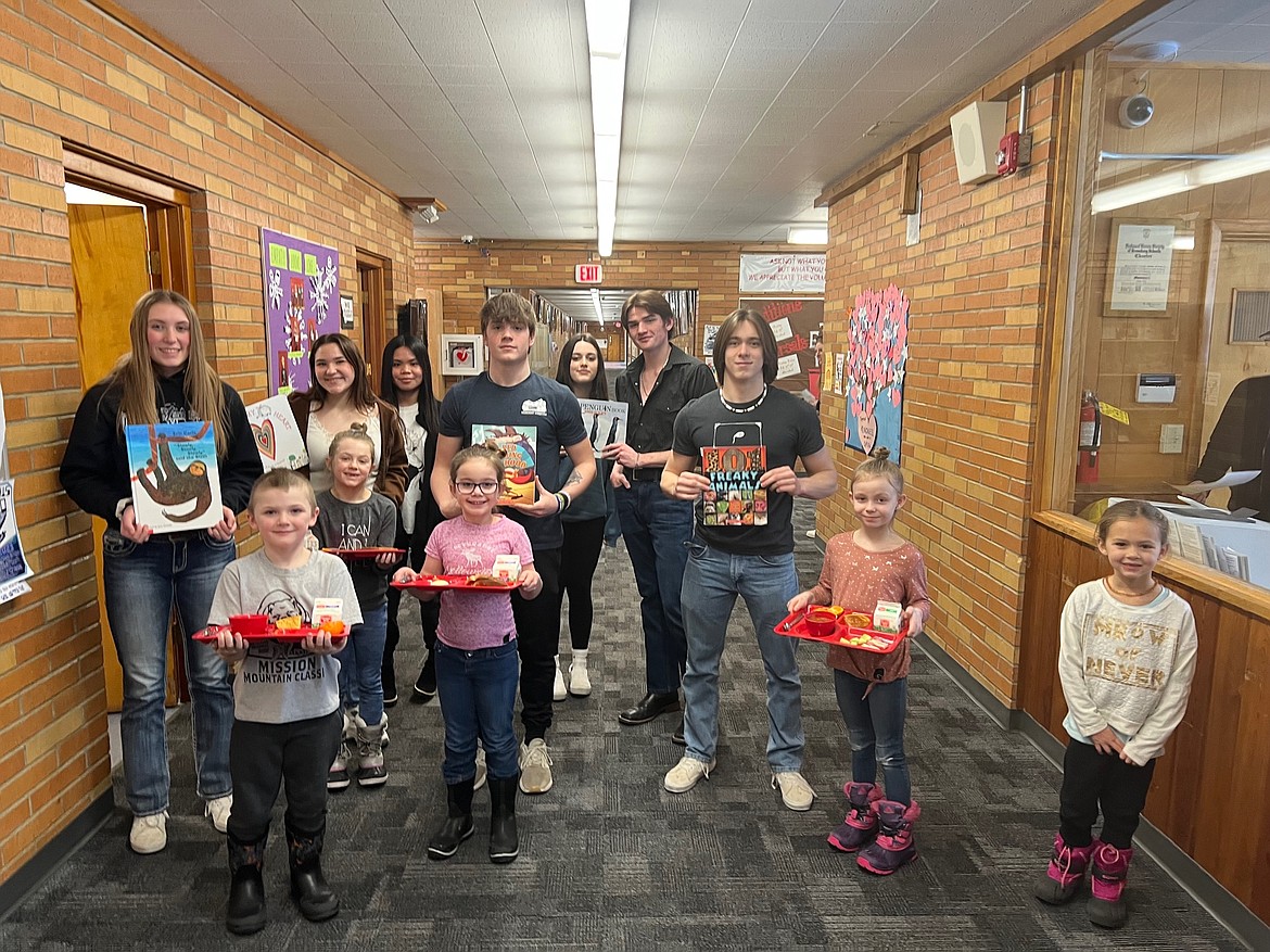 Noxon juniors read to elementary students during I Love to Read month. From left, juniors Emma Swanson, Farrah Ushia, Sofia Pelobello, Shamus Wheeldon, Mia Vogel, Michael Byrd and Owen Ramsey. First-greaders Vance Zeretzke, Brooklyn Posselt, Sadie Pederson, Kloe Kair and Eloise Oldenburg.