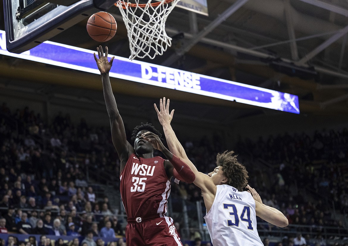 WSU forward Mouhamed Gueye, left, drives to the rim against Washington on March 2. Gueye is averaging 14.5 points and 8.6 rebounds per game this season, the latter being the second-most in the Pac-12.