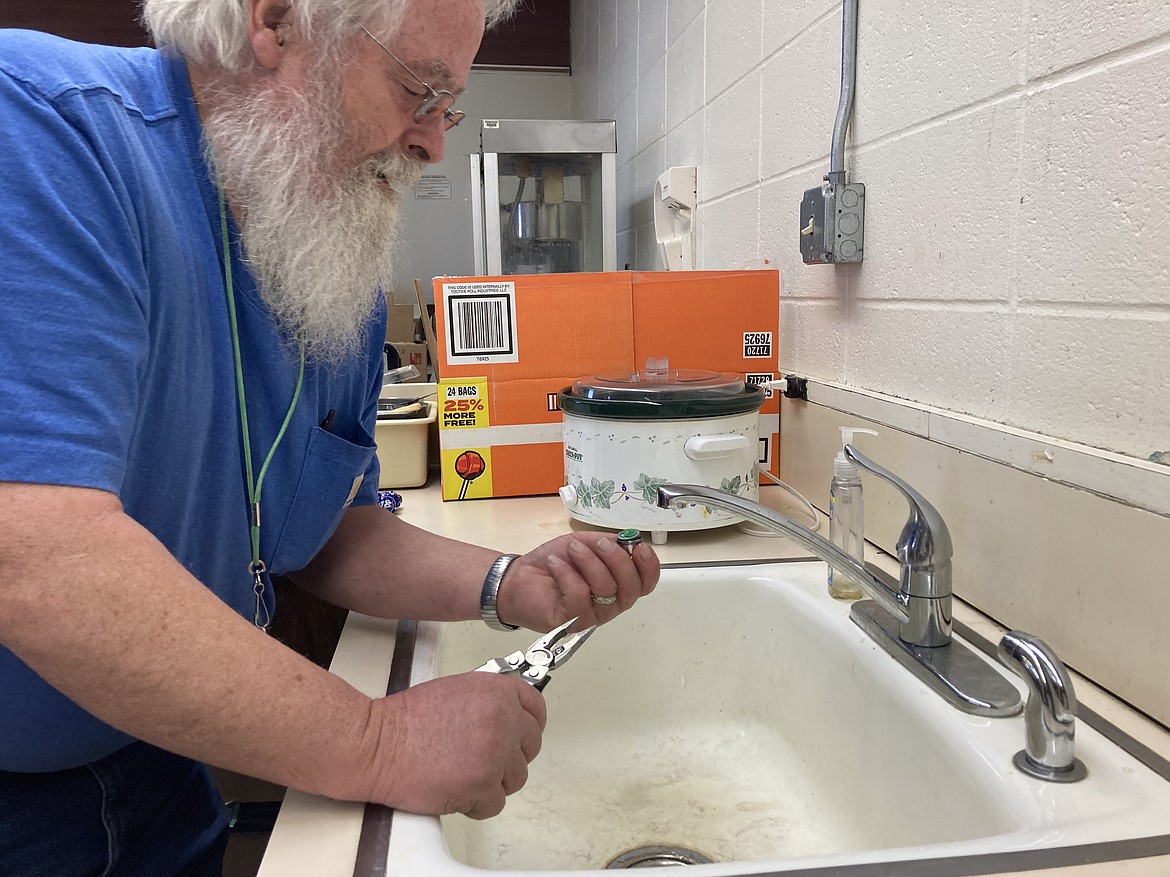 Chris Cornelius, head custodian of Philipsburg Public Schools in Montana, checks a faucet filter in a home economics classroom. Despite a new faucet and inlet pipes, this sink is one of several in the district that continue to show lead levels beyond the state’s threshold. (Katheryn Houghton/KHN)