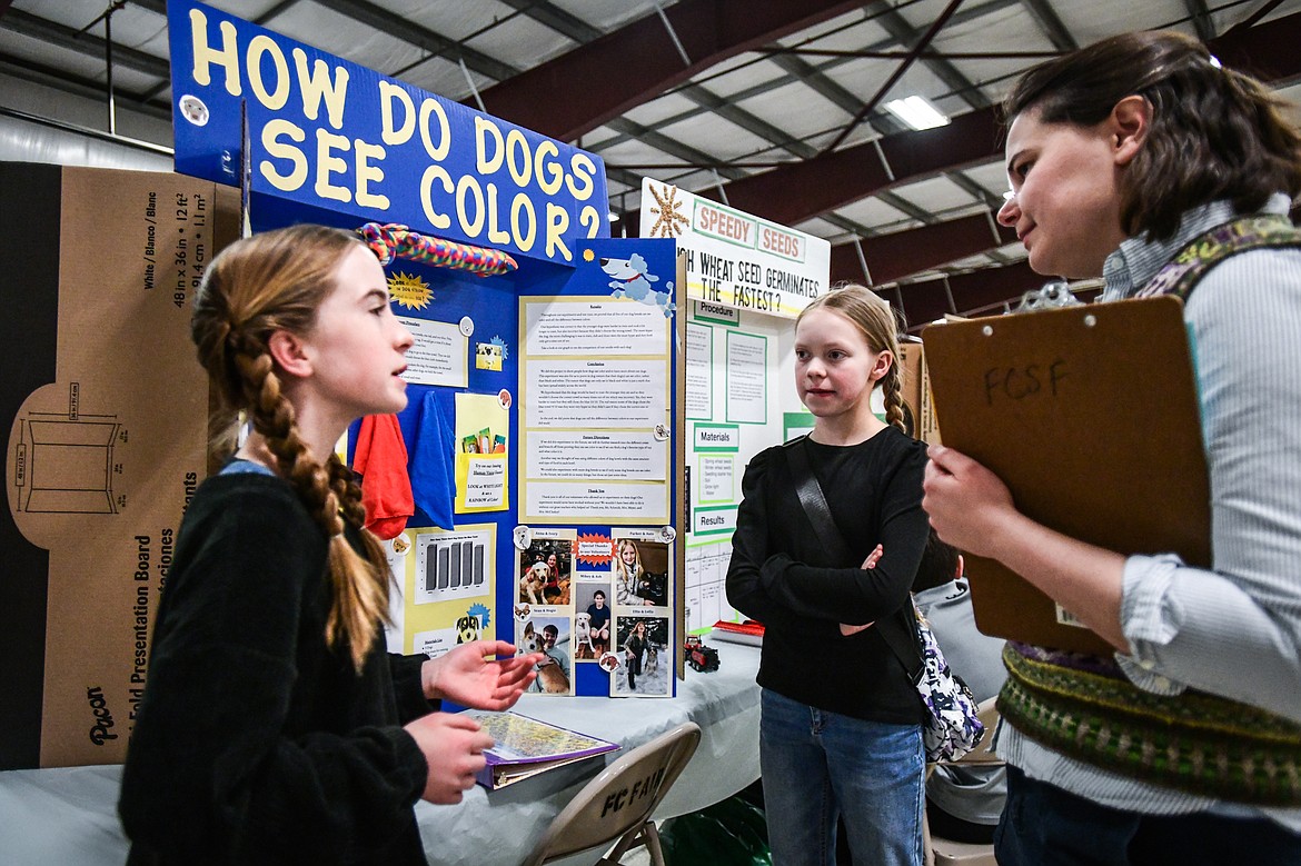 Anna Vincent, left, and Madilyn Isles, center, sixth-graders at Helena Flats School, discuss their project titled "How Do Dogs See Color?" with judge Indigo Scott at the Flathead County Science Fair at the Flathead County Fairgrounds Expo Building on Thursday, March 9. (Casey Kreider/Daily Inter Lake)