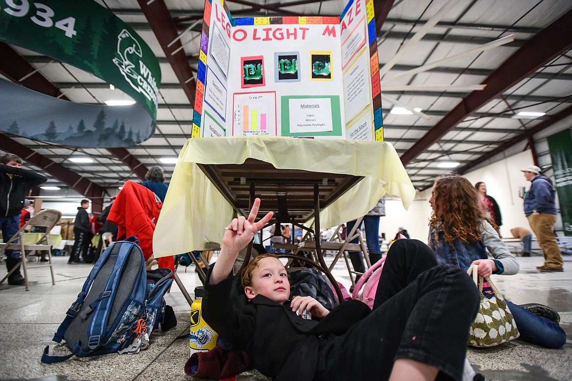 Ledger Street, a third-grader at Glacier Gateway Elementary, takes a snack break under his project titled "Lego Light Maze" at the Flathead County Science Fair at the Flathead County Fairgrounds Expo Building on Thursday, March 9. (Casey Kreider/Daily Inter Lake)