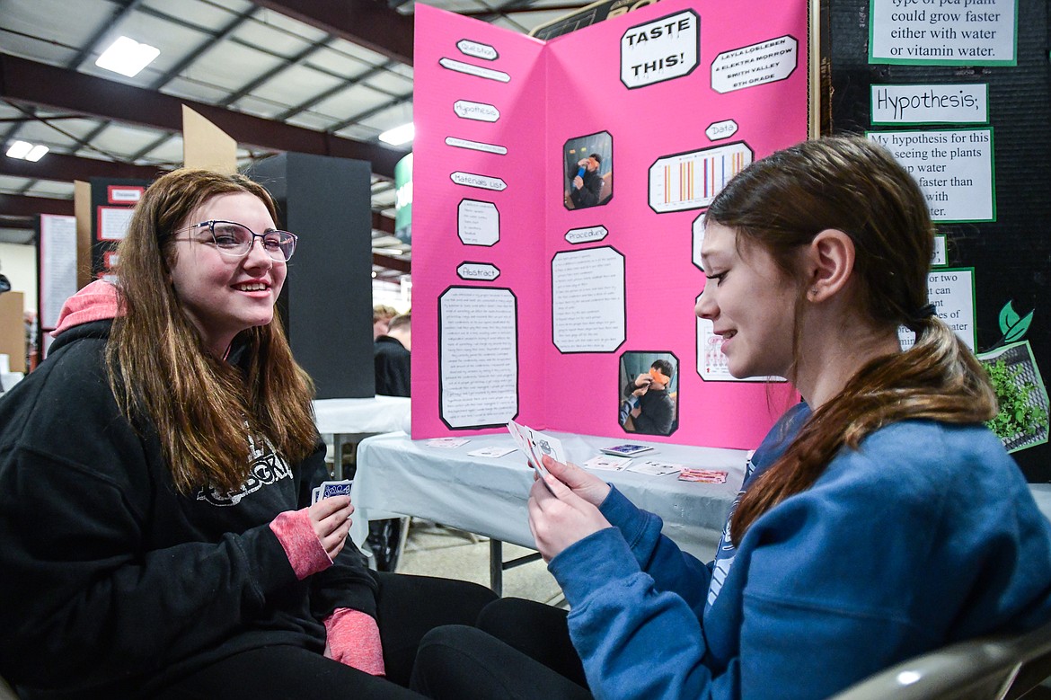 Elektra Morrow, left, and Layla Losleben, eighth-graders from Smith Valley School, play a game of "Go Fish" while they wait for the next judge at the Flathead County Science Fair at the Flathead County Fairgrounds Expo Building on Thursday, March 9. (Casey Kreider/Daily Inter Lake)