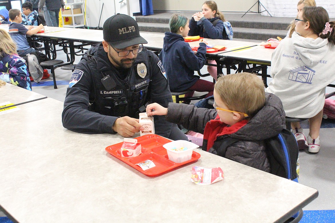 Moses Lake Police Department Officer Ian Campbell helps open a milk carton during breakfast at Groff Elementary.