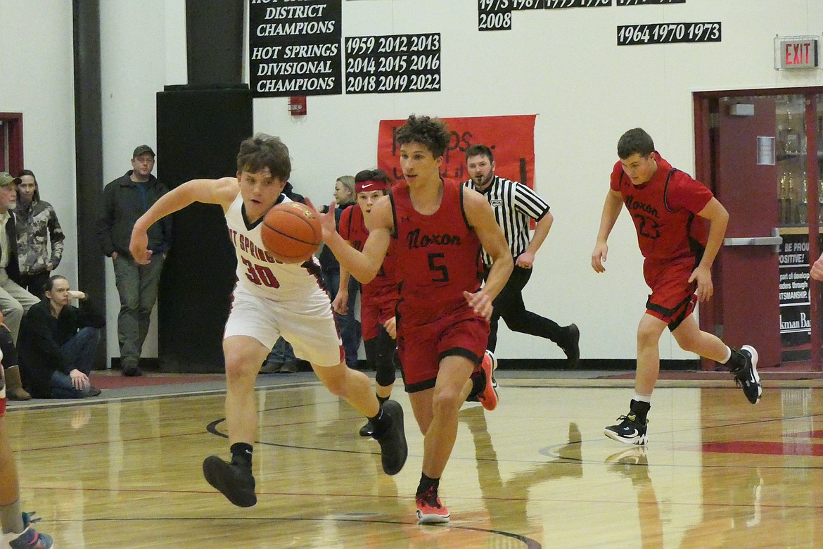 Hot Springs senior Garth Parker (white jersey, 30)  tries to get a hand on the ball dribbled by Noxon sophomore Ricky Williams during a game between the two teams in Hot Springs. Both players were recently named to the District 14C all-star team. (Chuck Bandel/VP-MI)