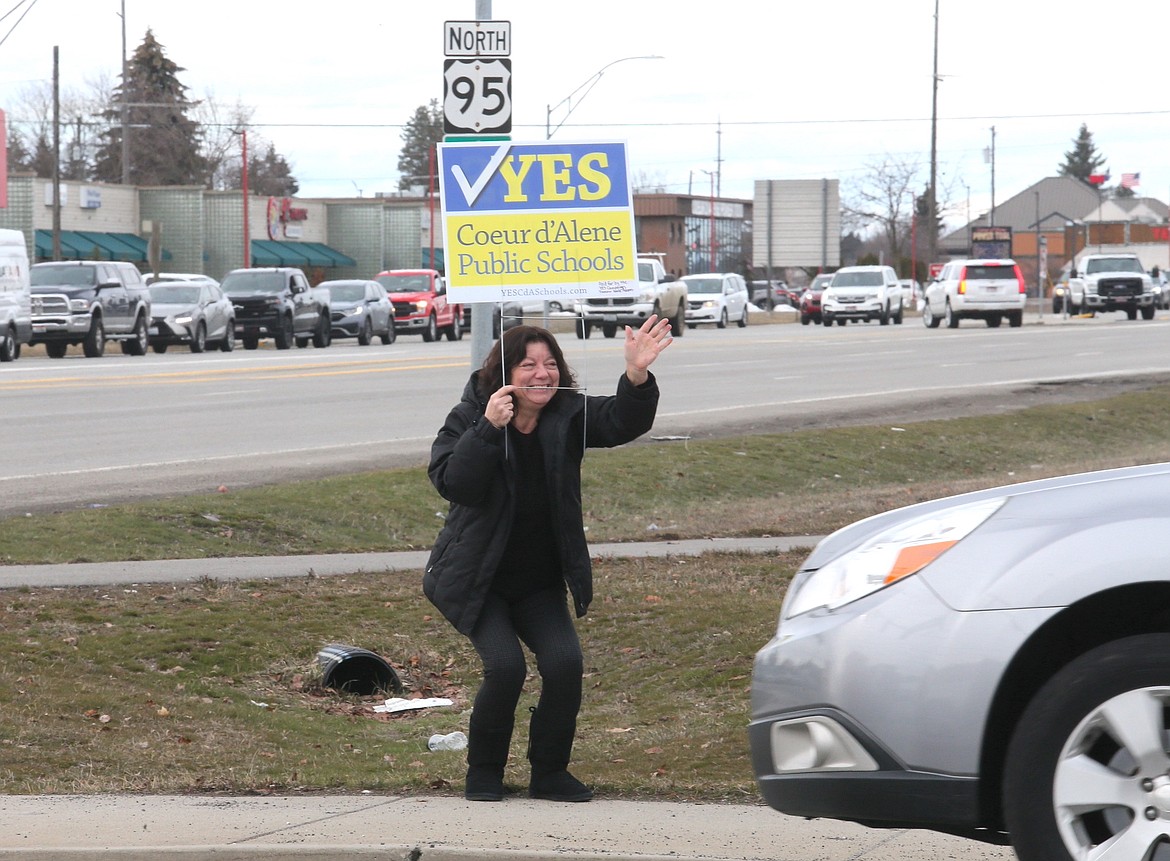 Marcy Canale, who has taught in the Coeur d'Alene School District for 25 years, waves to drivers on Appleway Avenue on Tuesday while holding a sign encouraging voters to vote in support of the district's levy elections.