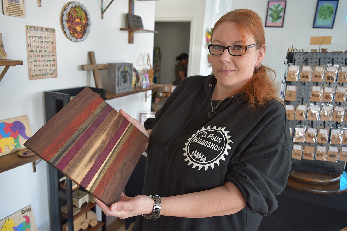 Samantha Simmonds holds up a cutting board made of exotic hardwoods she sells at her new shop A Plus Woodshop, which she owns with her husband A.J. — the maker of the cutting board.