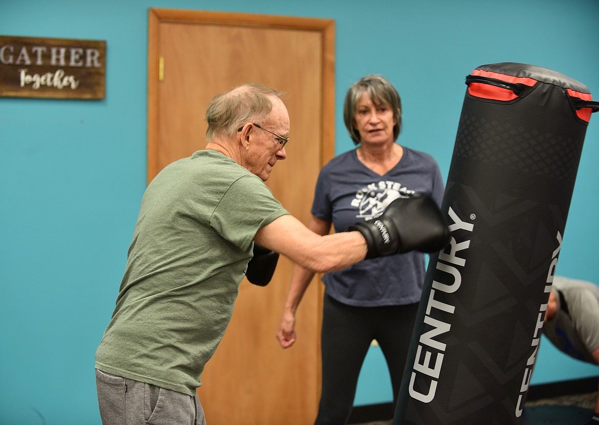 Curt Peterson punches a boxing bag while his wife Jan offers support during a Rock Steady Boxing — Glacier class Monday, March 13, 2023 at Gateway Community Center in Kalispell. The no-contact boxing-based fitness program helps people with Parkinson's disease work on eye-hand coordination, movement and strength. (Hilary Matheson/Daily Inter Lake)