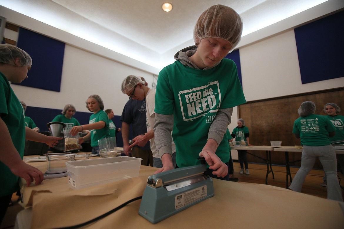 Sophomore Chase Brinton vacuum seals a meal Thursday morning during the Feed the Need packing party at North Idaho Christian School.