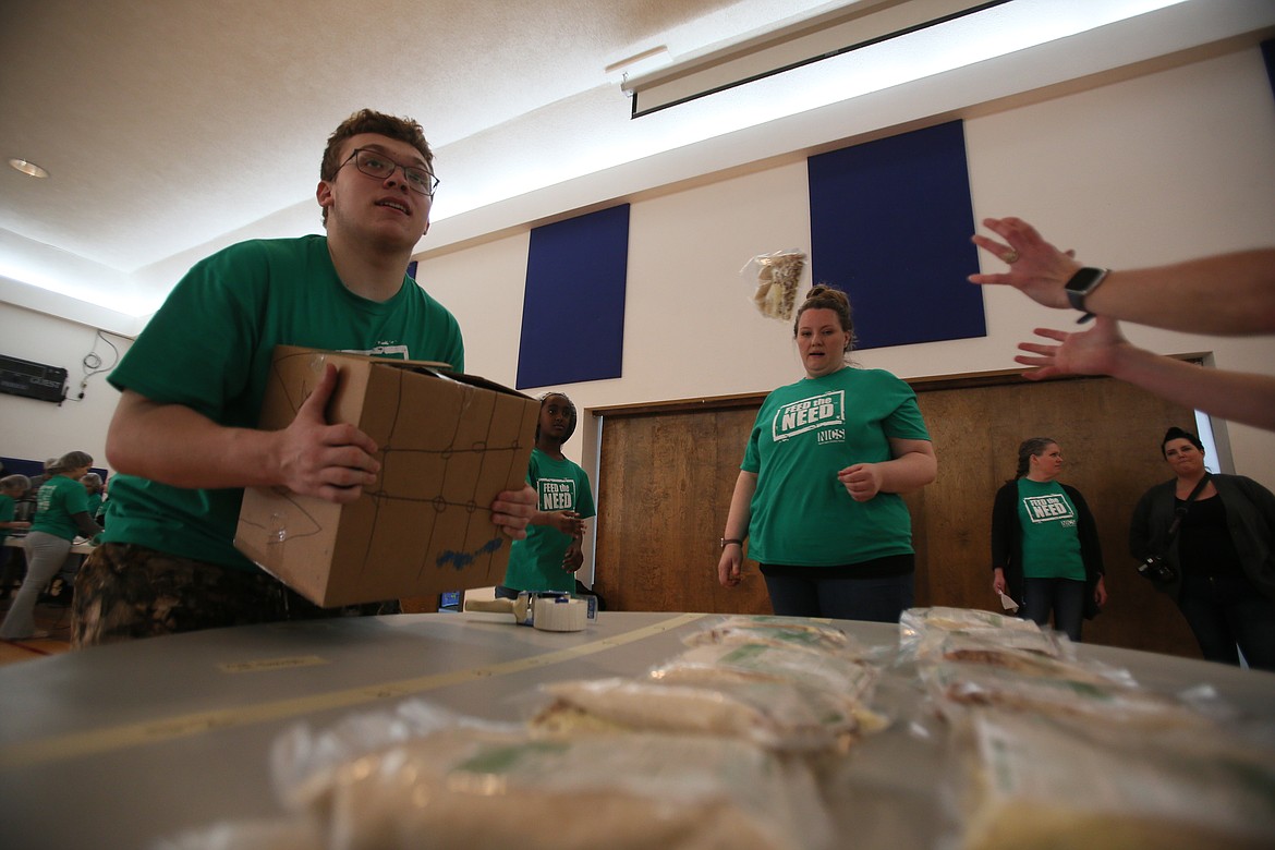 Senior Victor Badger hauls a box of prepared bean and rice meals Thursday morning as he and his schoolmates pack 10,000 meals for children in need in Haiti.