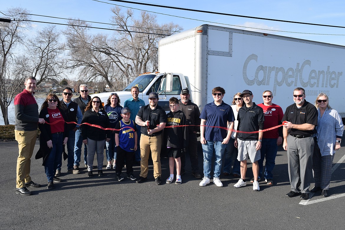 Dylan Morris, owner of Door to Door Moving in Moses Lake, cuts the ribbon Thursday afternoon on his new moving truck in the parking lot of the Moses Lake Chamber of Commerce at 606 W. Broadway while surrounded by family members, employees and Chamber of Commerce members.