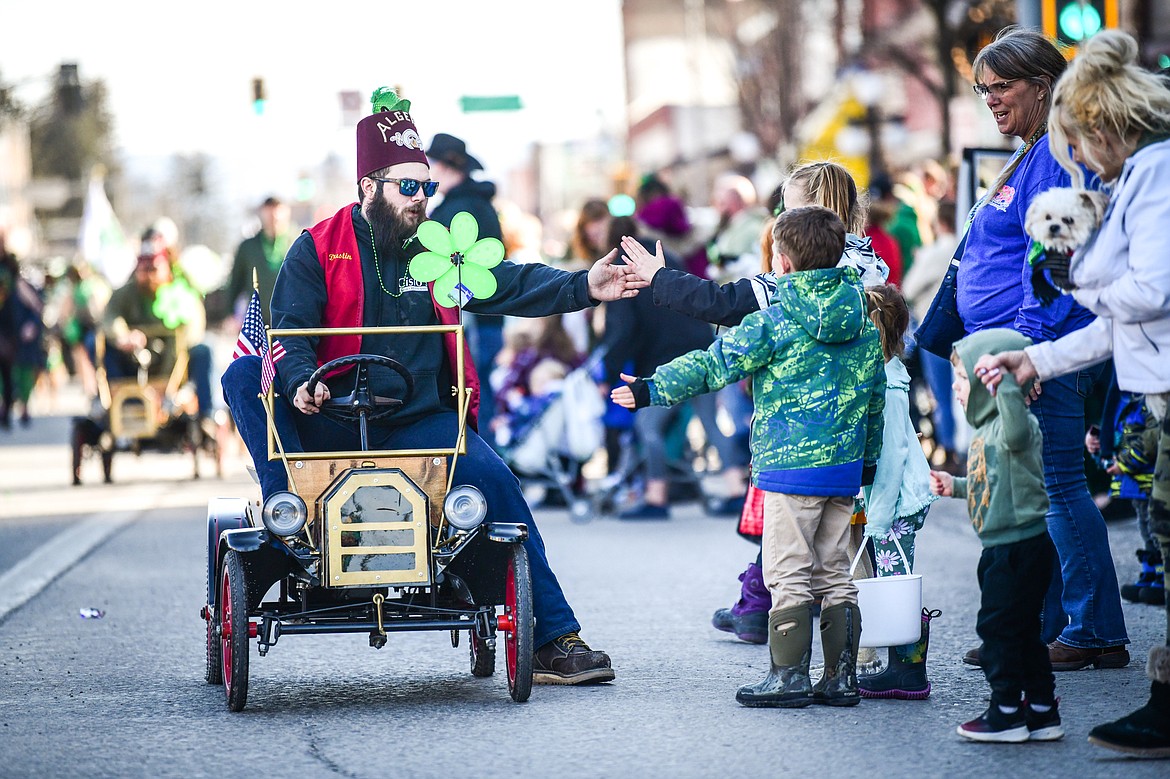 A member of the Flathead Shrine Club high-fives his way down Main Street  during the St. Patrick's Day Parade in Kalispell on Friday, March 17. (Casey Kreider/Daily Inter Lake)