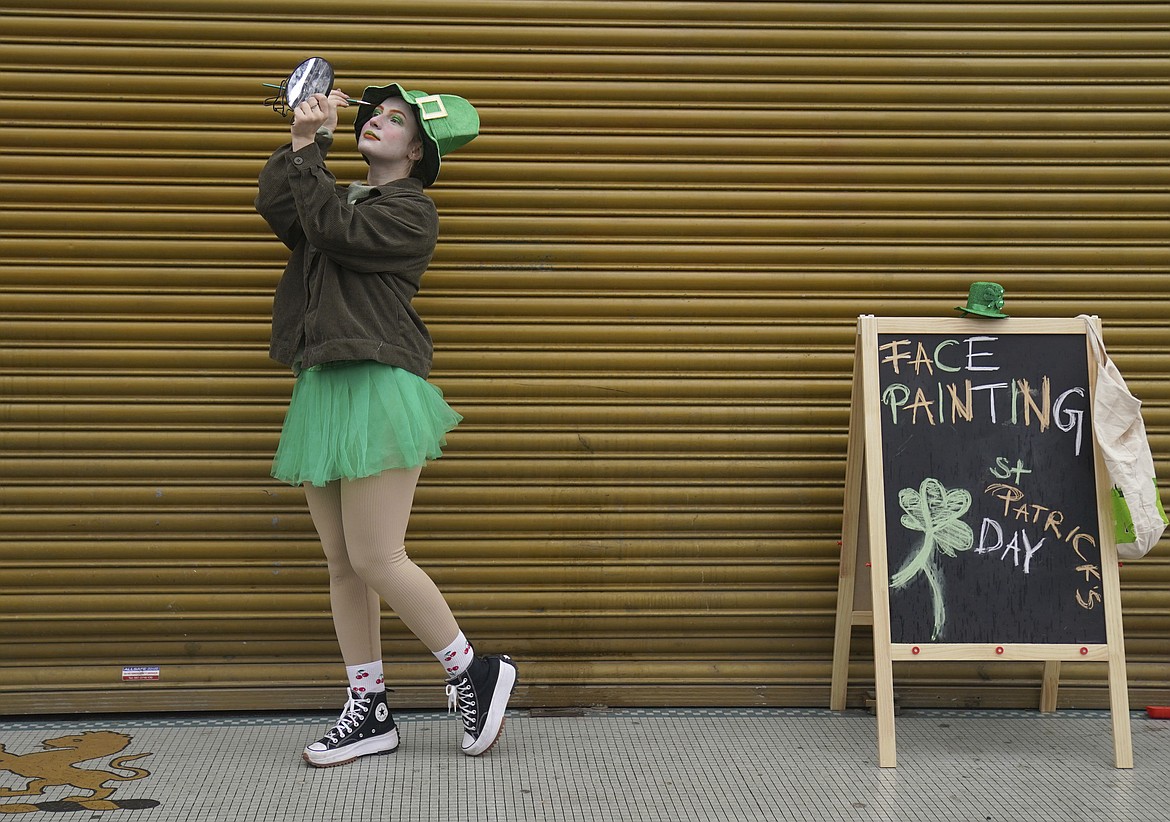 A face painter applies eye shadow, ahead of the St Patrick's Day Parade in Dublin, Friday March 17, 2023. (Brian Lawless/PA via AP)