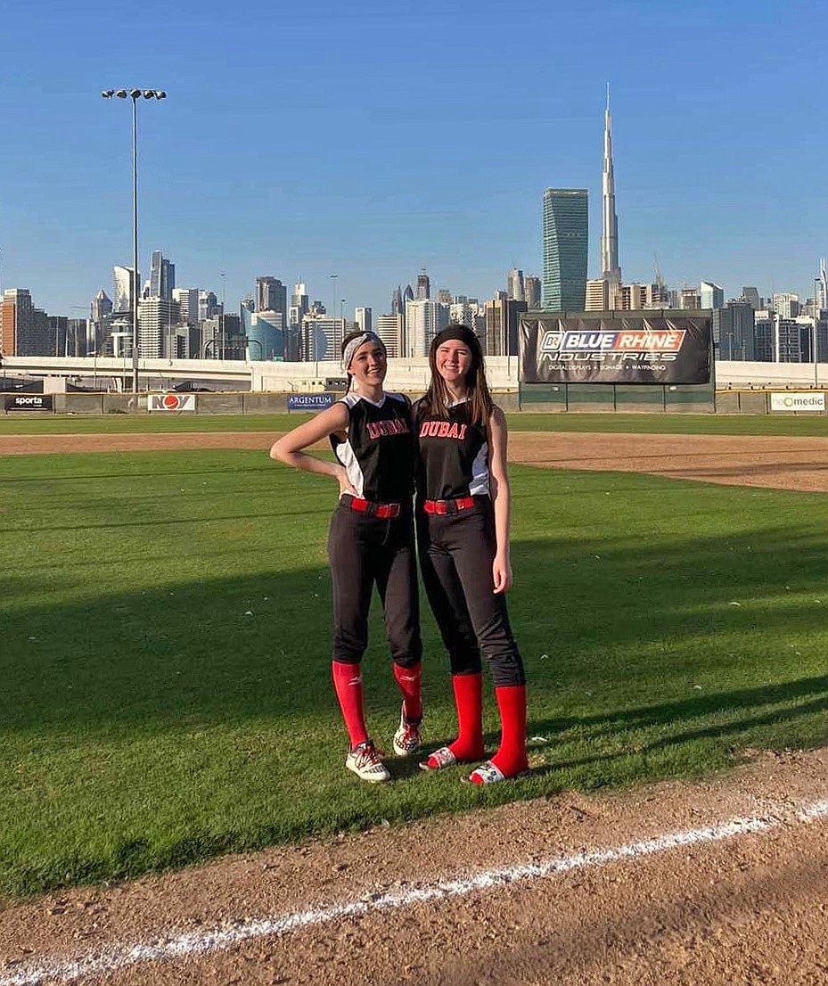 Macy Whisenand and her sister, Alyssa, at their home softball field with the skyline of Dubai in the background. (Photo provided)