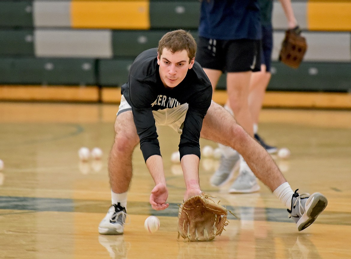 Whitefish's Michael Miller scoops up a ball during a drill at baseball practice in the WHS gym on Wednesday, March 15. (Whitney England/Whitefish Pilot)