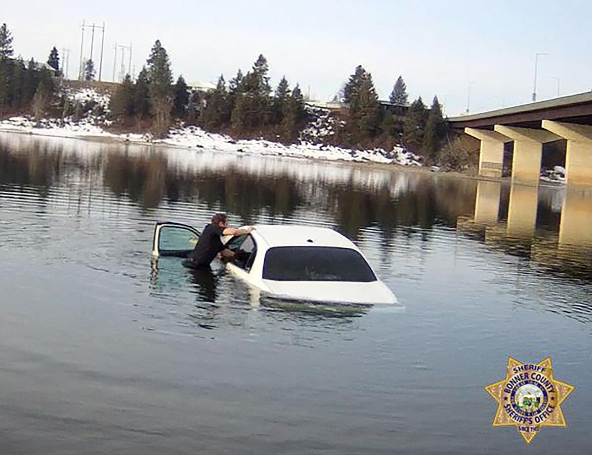 Deputy Clevy Santos reaches into a partially submerged vehicle to grab a hold of an elderly woman whose vehicle had ended up in the Pend Oreille River about 20 to 30 feet for shore near the Oldtown boat launch.