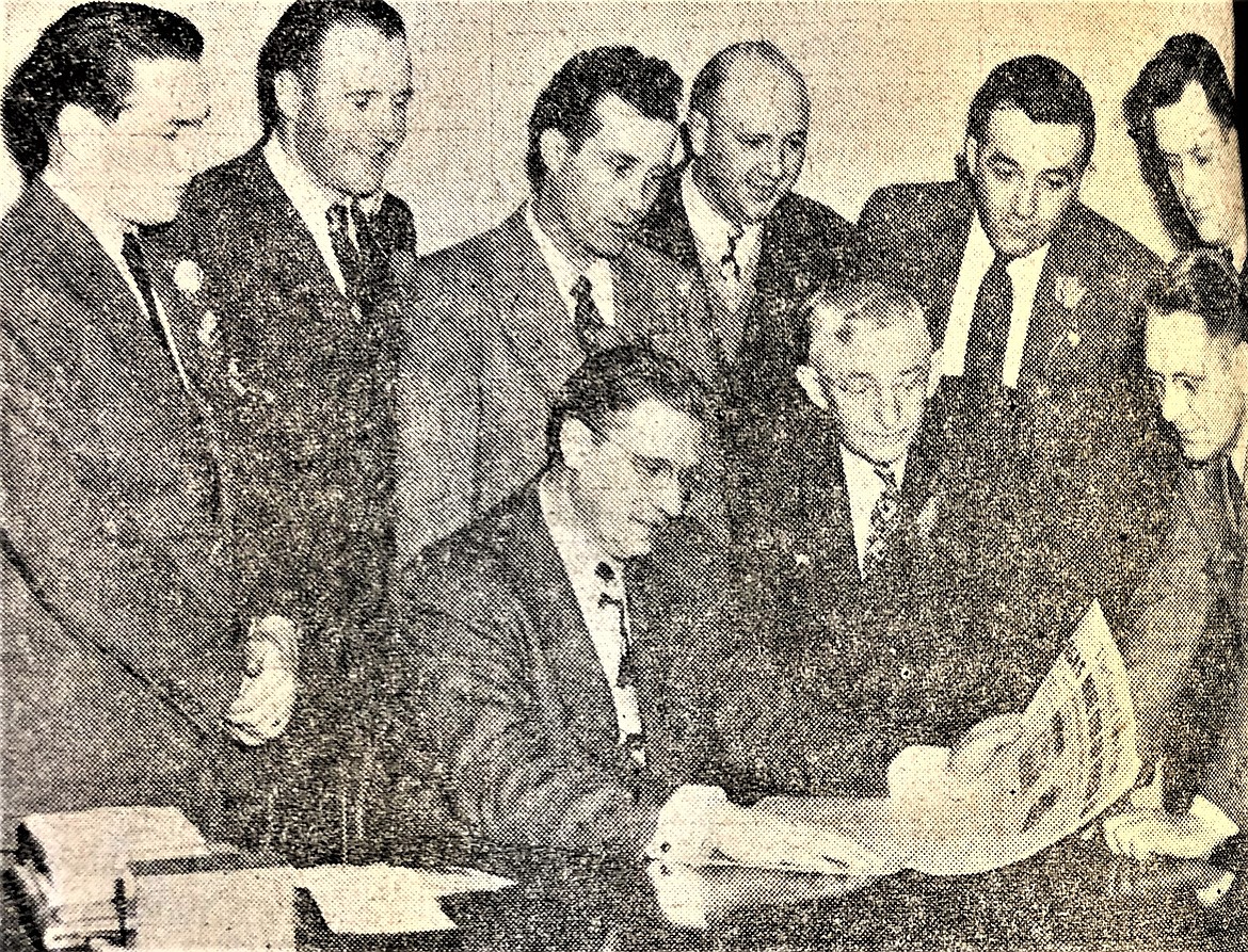 Publisher Burl Hagadone reads his Press at the paper's 1948 open house, surrounded by radio representatives.