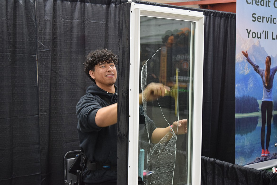 Kevin Farias, 22, the owner of Caged Cleaning in Moes Lakes, uses a Squeegee to wipe off a window and show off his company at the Moses Lake Chamber of Commerce’s annual Business Expo on Tuesday.