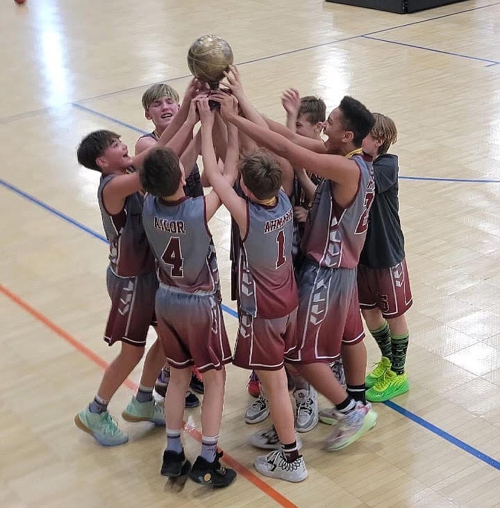 Moses Lake Tribe players smile and cheer on the court with the first-place trophy from the 2023 Washington Middle School Basketball Championship.