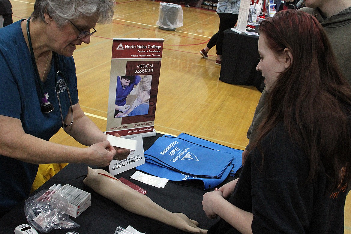 Cindy Pavel guides a student on how to close an open wound at the medical assistant booth at the North Idaho College Roadshow, held Friday at Sandpoint High School.