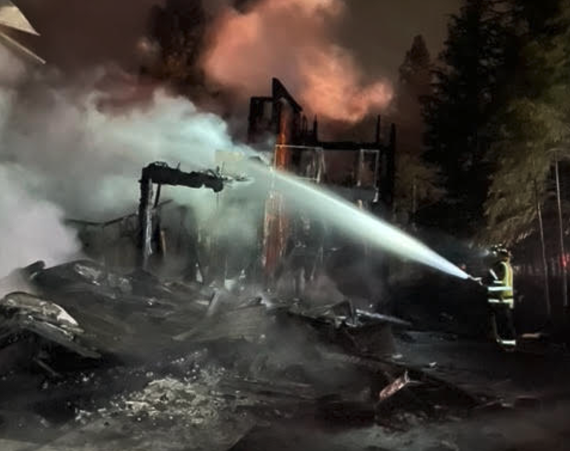 East Side Fire District firefighters work to extinguish flames that engulfed two residential structures Monday night at Gozzer Ranch.