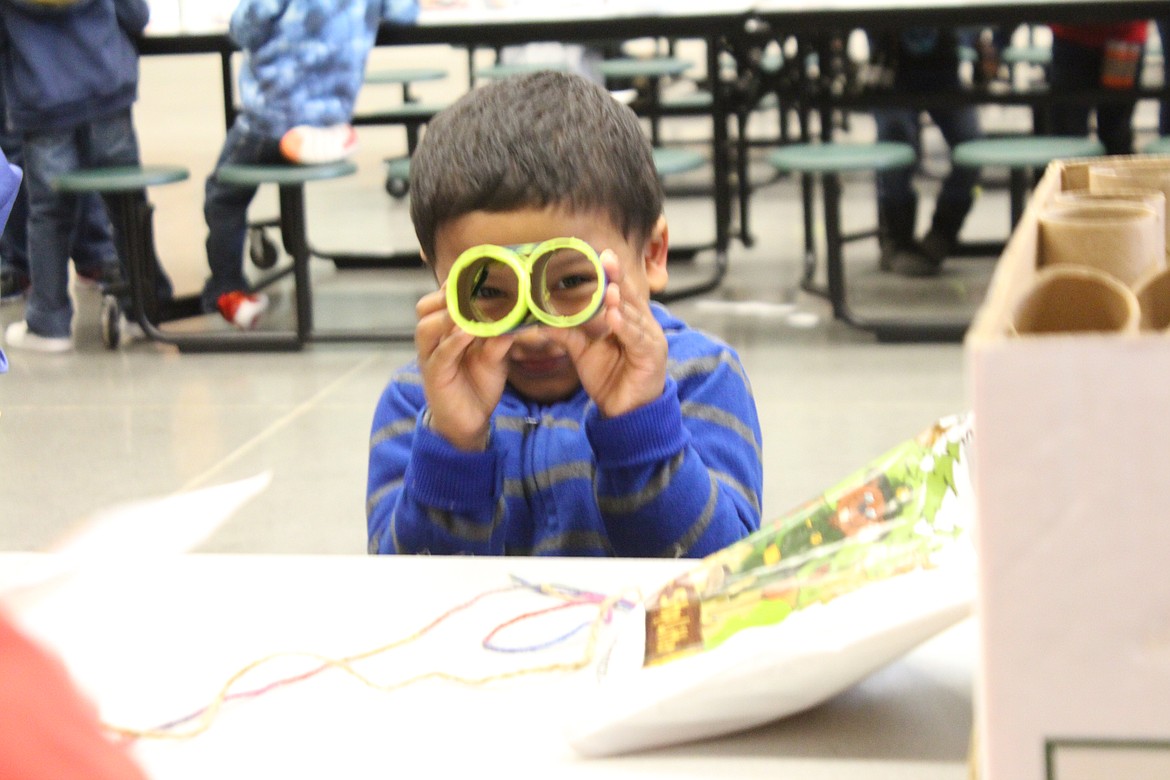 Izak Valencia takes a peek through his birdwatching binoculars, one of the crafts available to children at the Othello Sandhill Crane Festival Saturday.