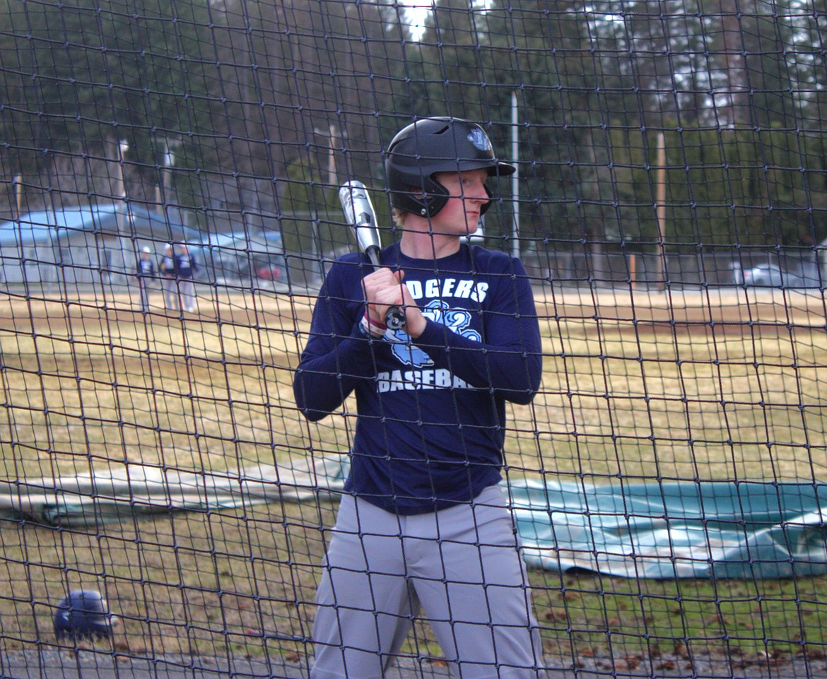 Henry Willis practices swing in battling cage at practice.