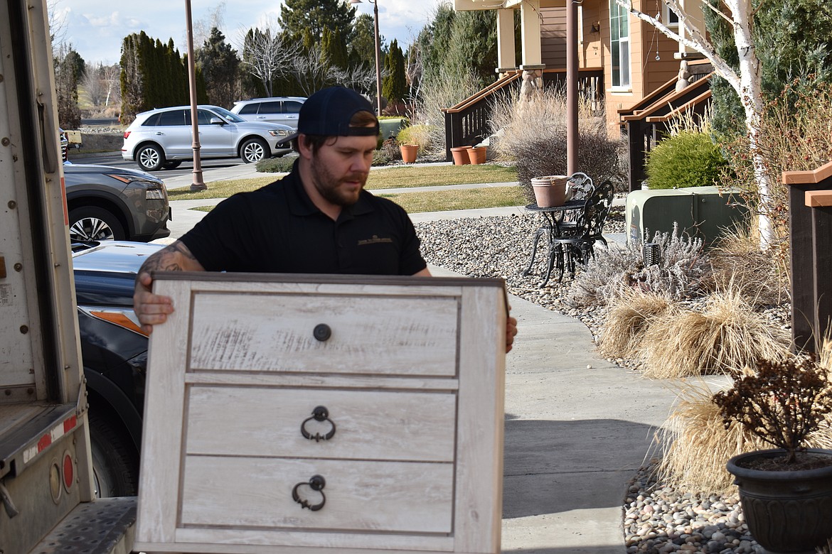 Dylan Morris, owner of Door to Door Moving in Moses Lake, moves a dresser out of the truck for a client.