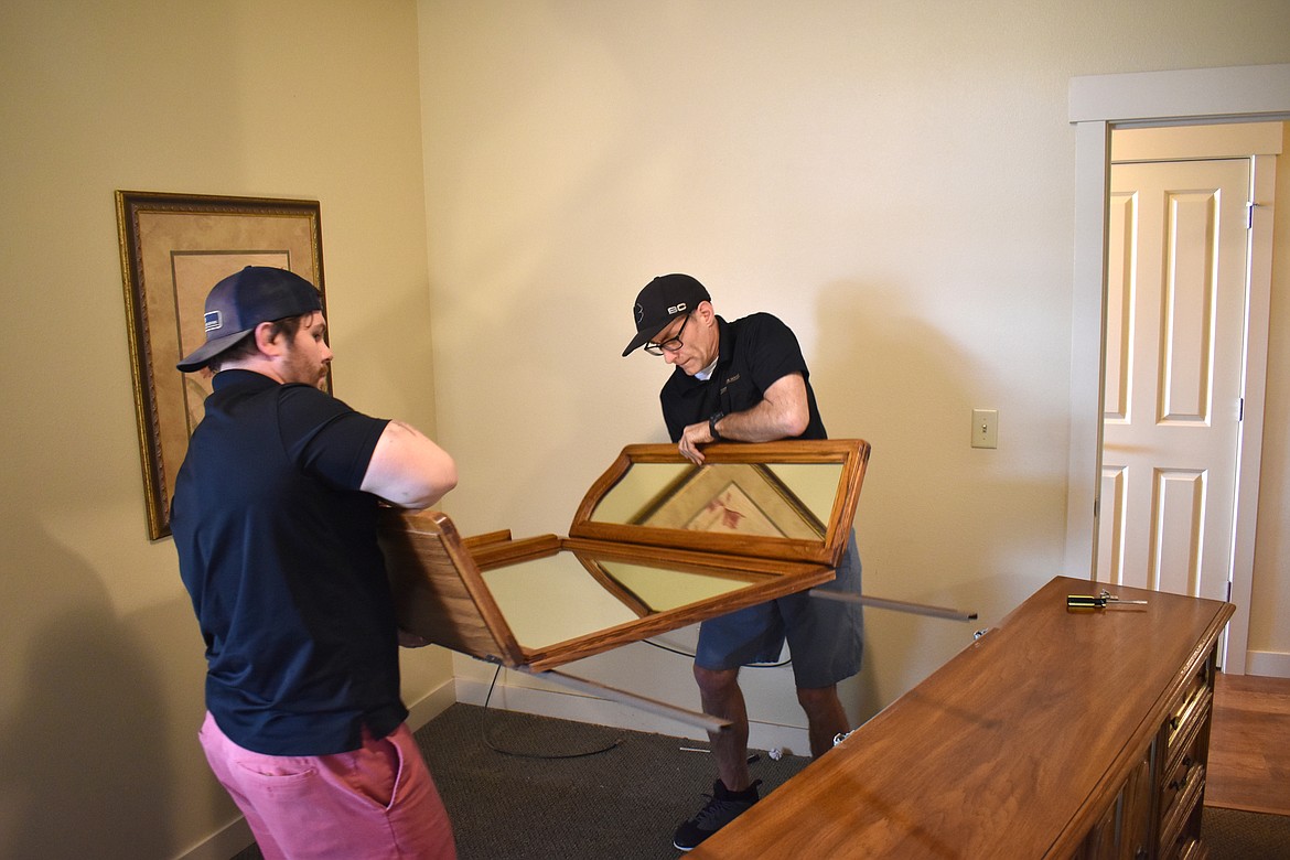 Dylan Morris, left, and Redgy Smith of Door to Door Moving wrestle with a piece of furniture.