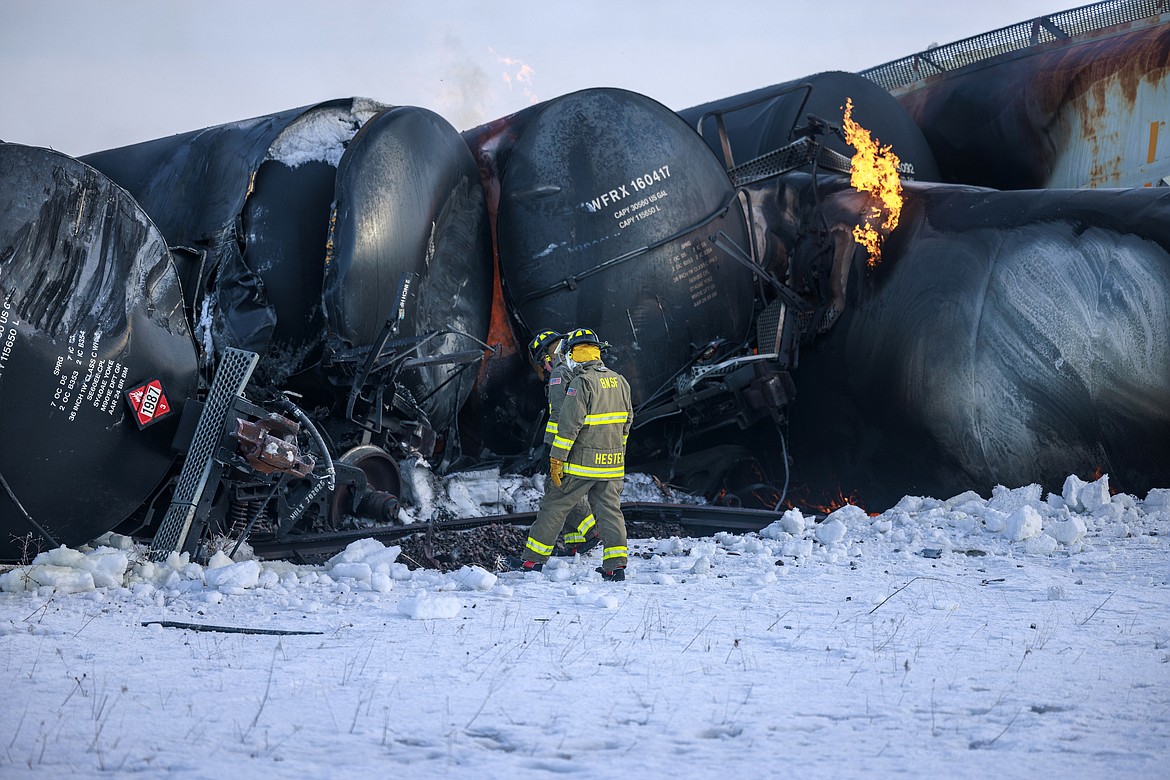 Firefighters work near piled up train cars, near Raymond, Minn., Thursday, March 30, 2023, the morning after a BNSF freight train derailed. Authorities say a train hauling ethanol and corn syrup derailed and caught fire and residents within 1/2 mile of the crash were ordered to evacuate from their homes. (Kerem Yücel/Minnesota Public Radio via AP)