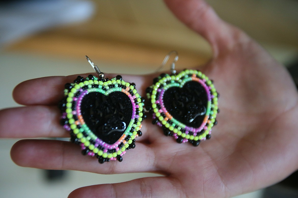 Lake City High School senior and Coeur d'Alene Tribal member Amya Sines holds up a set of beaded earrings she created for "The Exhibit" student art show that will be Wednesday through Friday at the Harding Family Center.