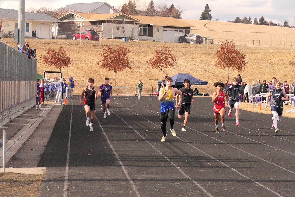 Thompson Falls senior Breck Ferris (Blue/Yellow jersey) sprints toward a second place finish in the men's 100 meters sprint during Friday's Dave Tripp Memorial meet in Polson.  (Chuck Bandel/VP-MI)