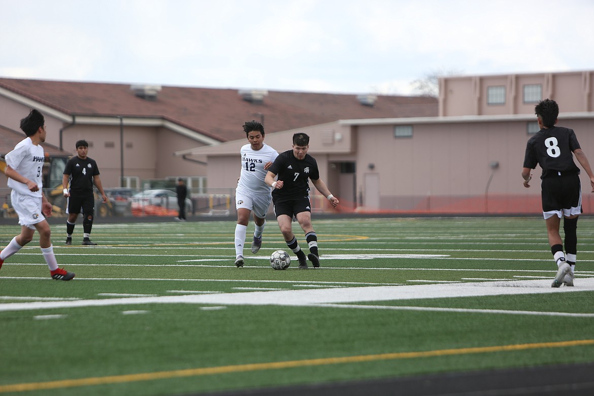 Royal senior Kaleb Hernandez (7) gets past a College Place player before passing the ball to a teammate.