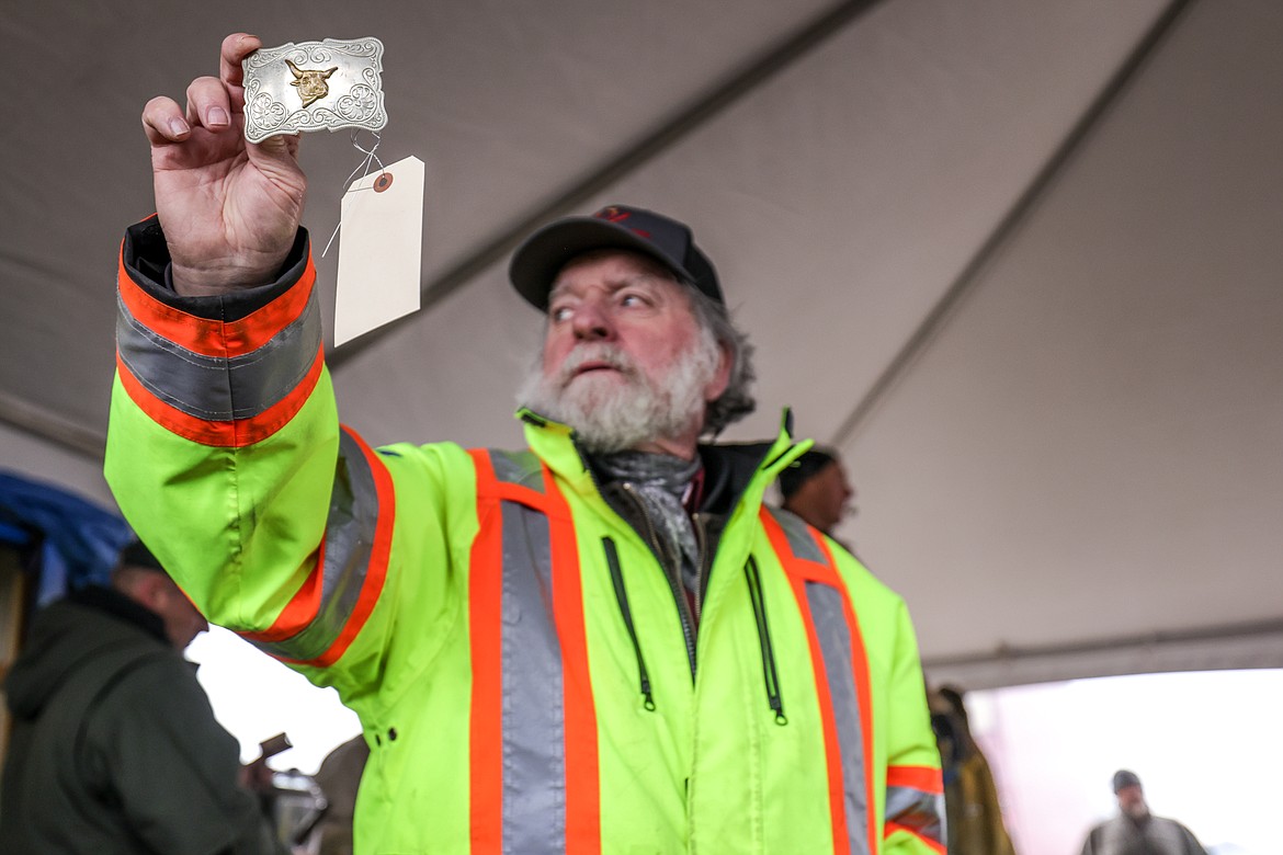 A Creston firefighter holds up a belt buckle for sale at the Creston Auction on Saturday. (JP Edge photo)