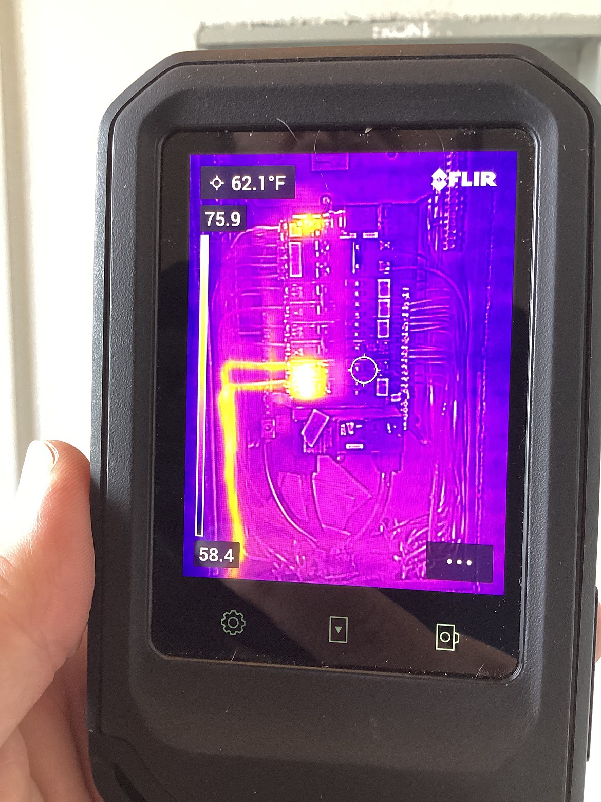 Henry Counter uses an infrared sensor to check the temperature of electrical wiring and connections. The small white circle in the middle indicates the target area, which is at 62.1 degrees Fahrenheit, while the numbers to the side show the complete temperature range. These numbers are well within safe parameters, he said.