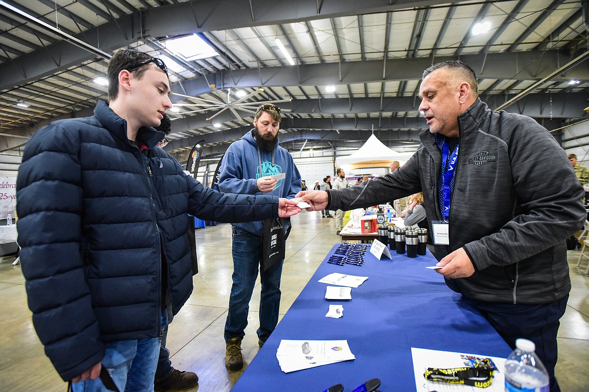 Armando Oropeza, with the Montana Department of Justice, hands out his business card to job-seekers at the NWMT Job & Opportunity Fair inside the Trade Center at the Flathead County Fairgrounds on Thursday, April 6. (Casey Kreider/Daily Inter Lake)