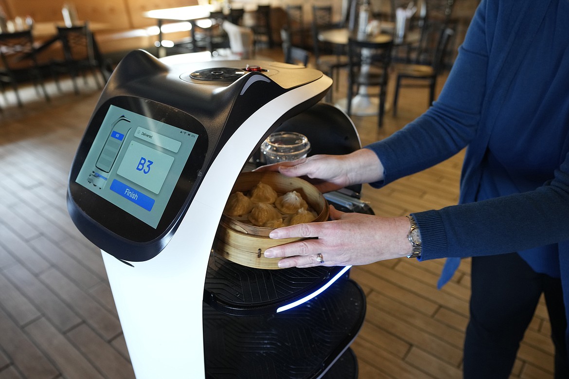 A customer receives a meal delivered by a BellaBot robot at the Noodle Topia restaurant on Monday, March 20, 2023, in Madison Heights, Mich. Many think robot waiters are the solution to the industry’s labor shortages and sales have been growing rapidly in recent years, with tens of thousands now gliding through dining rooms worldwide. (AP Photo/Carlos Osorio)