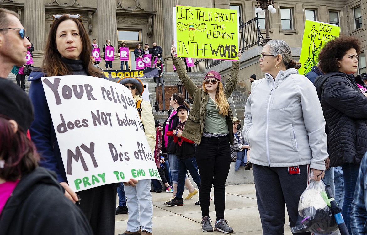 Boise resident Autumn Myers holds a sign with the Republican Party elephant symbol inside the outline of a uterus that reads, "Let's talk about the elephant in the womb," during a Planned Parenthood rally for abortion rights in downtown Boise, May 14, 2022. Idaho Gov. Brad Little has signed a bill into law that makes it illegal for an adult to help a minor get an abortion without parental consent.