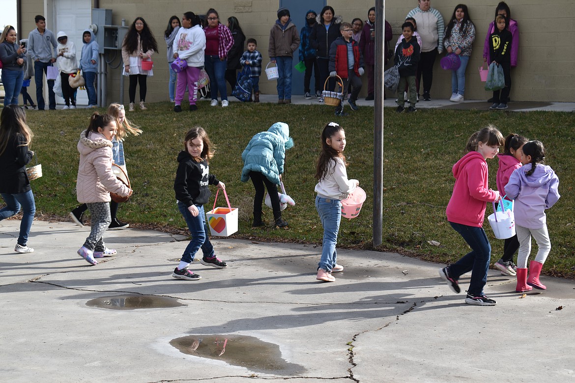 The 7- to 9-year-old girls run backward toward a field of eggs at the George Easter egg hunt, while the boys wait for their signal to bunny-hop behind them.