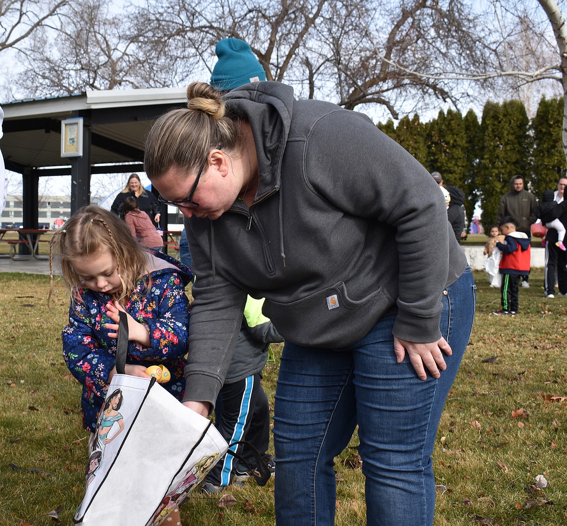 Lyra Bushman, 4, gets a little help from her mom, Rebekah Bushman, at the George Easter egg hunt Saturday morning.