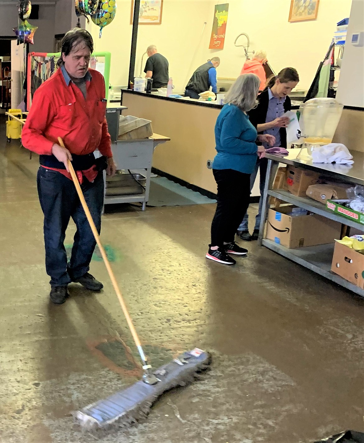 Dean Berkness sweeps and others clean up following Saturday night's soup kitchen operated by Cherished Ones Ministries.