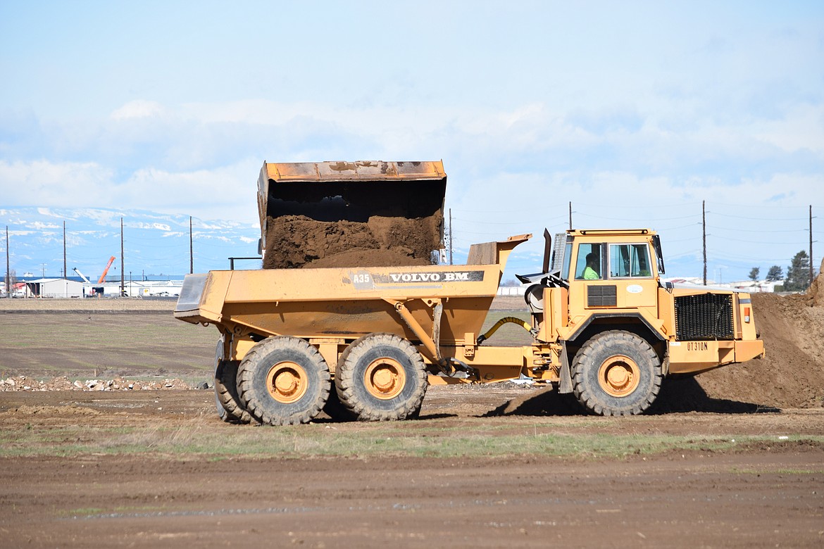 A front loader dumps dirt into a dump truck as construction workers begin the task of grading the ground where Group14 Technologies will have its new Moses Lake production facility.