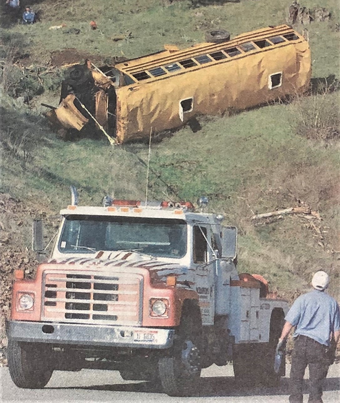 A wrecker removes crashed bus from hillside.
