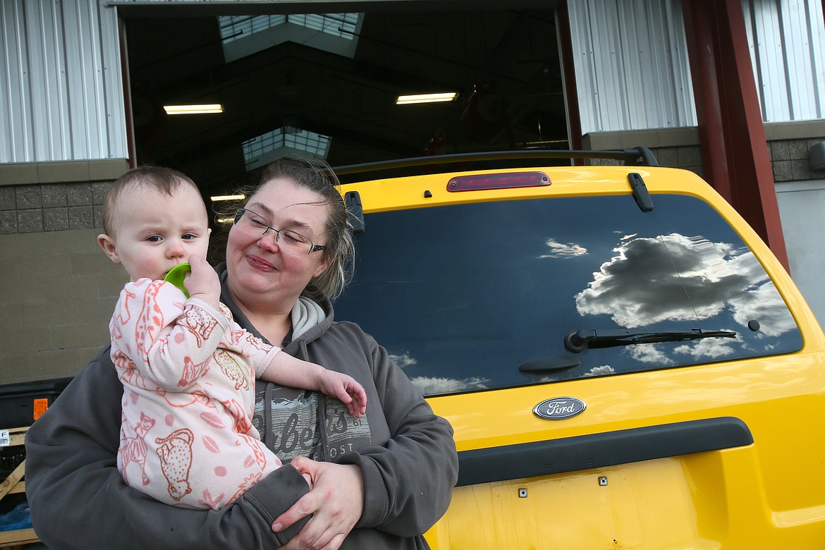 Natausha Green looks at her daughter, Meadow, Wednesday afternoon as they stand in front of the 2002 Ford Escape that Green is buying through a new car exchange program launched by Charity Reimagined, Kootenai Technical Education Campus and community partners. "This is my fresh start," Green said.