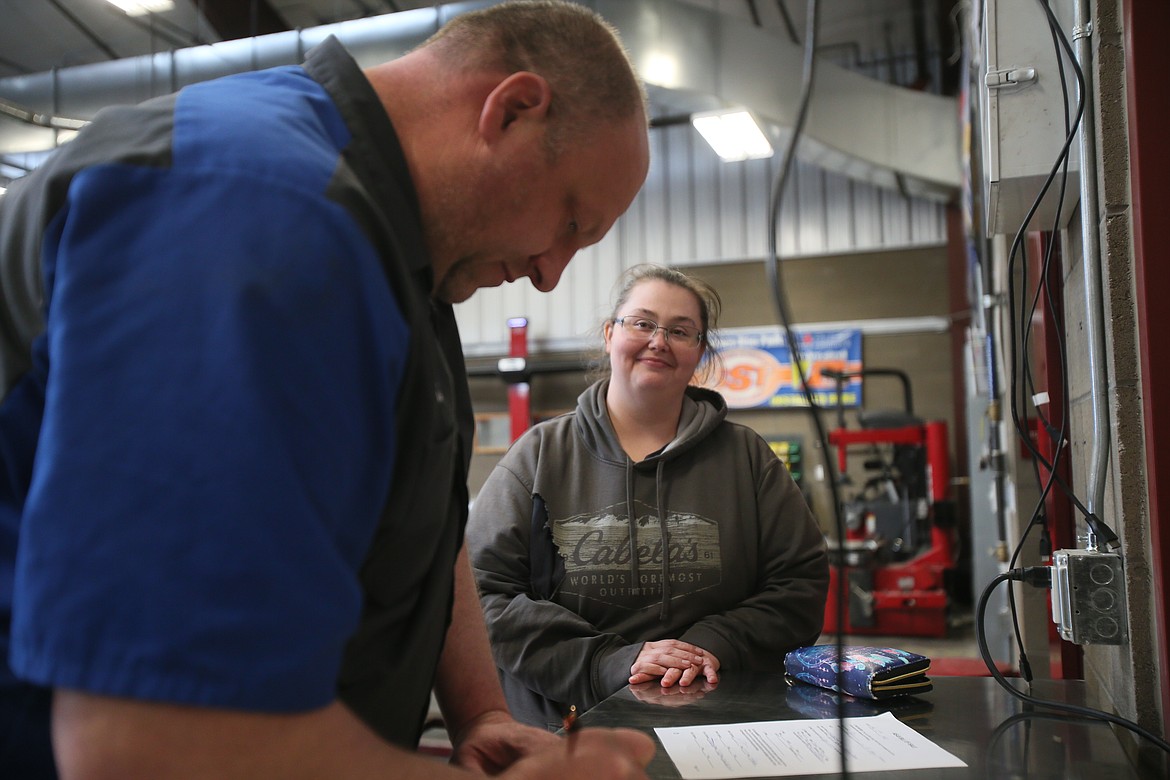 Natausha Green and KTEC auto instructor TJ Robertson fill out paperwork Wednesday before Green goes home with a vehicle she is buying through a new vehicle exchange program that will help people acquire vehicles at the price of parts, with repairs done by KTEC students to give them experience as they make the vehicles road ready.