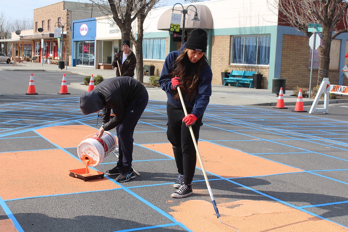 The design at the C Street intersection starts to take shape Thursday morning; Marissa Lopez, foreground, and Meredith Jones, background, apply the paint to the street.