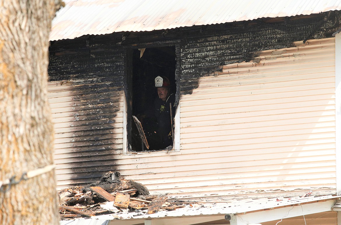 During an investigation on Thursday, Coeur d'Alene Fire Department Deputy Fire Marshal Bobby Gonder tosses a board from the upstairs of a home damaged in a fire Wednesday night.