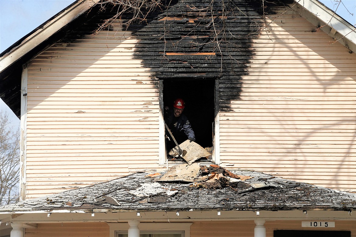 Coeur d'Alene Fire Department Deputy Fire Marshal Craig Etherton on Thursday moves material outside of the upstairs room of the Young Avenue home that was damaged in a fire Wednesday night.