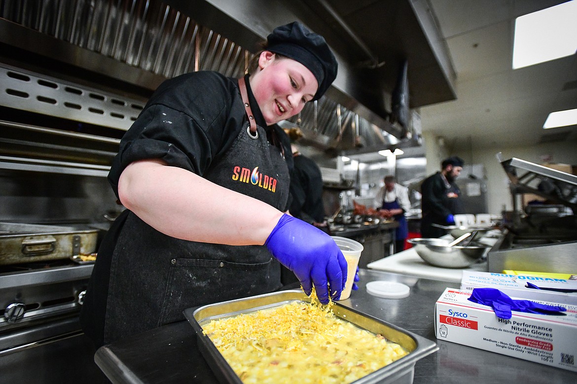 Chef Alexa Wood sprinkles a layer of cheese atop the macaroni and cheese at Flathead Valley Community College's pop-up lunch restaurant "Smolder," operated by students in the school's Culinary Institute of Montana on Thursday, April 13. (Casey Kreider/Daily Inter Lake)